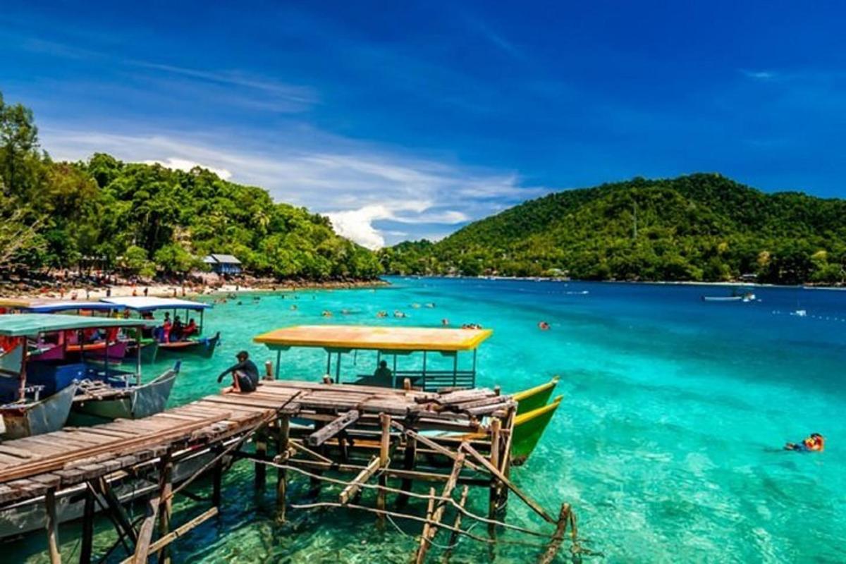 a dock with boats in the water next to a beach