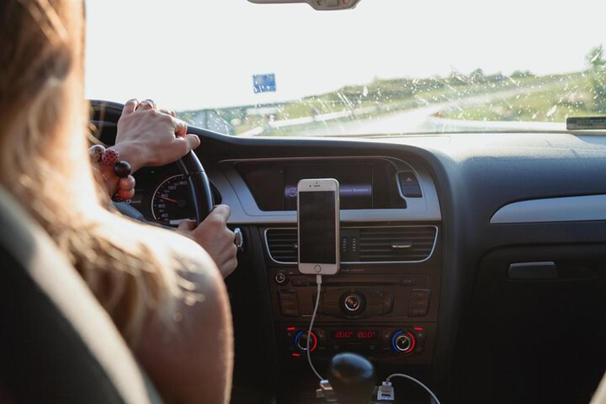 una dona conduint un cotxe amb un telèfon mòbil al volant