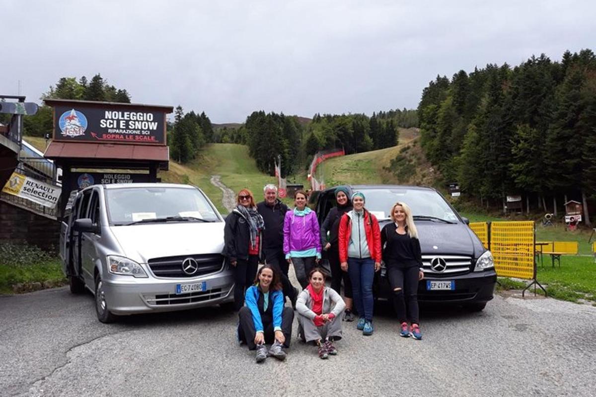 eine Gruppe von Menschen posiert vor zwei Autos