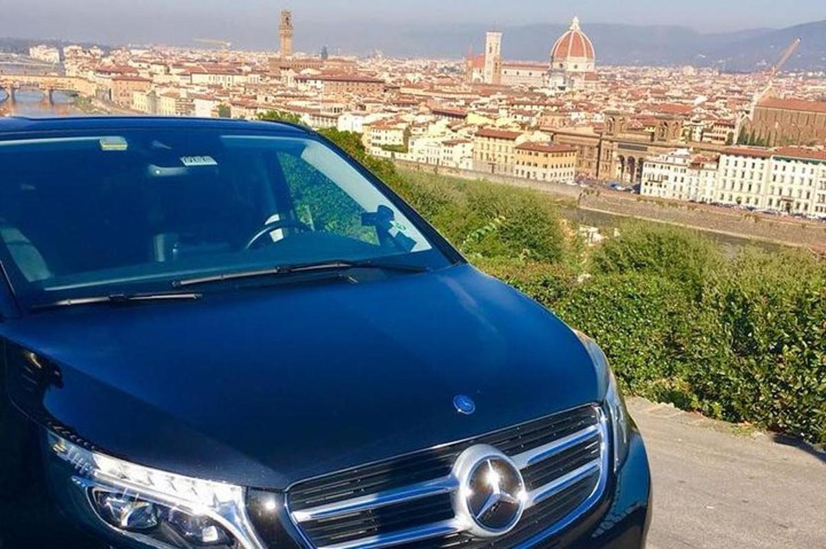un'auto blu parcheggiata su una collina che domina una città