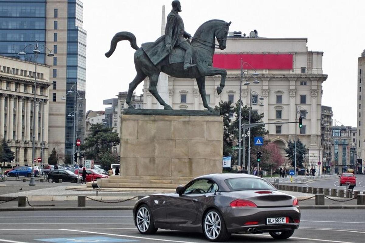 a car driving past a statue of a man riding a horse