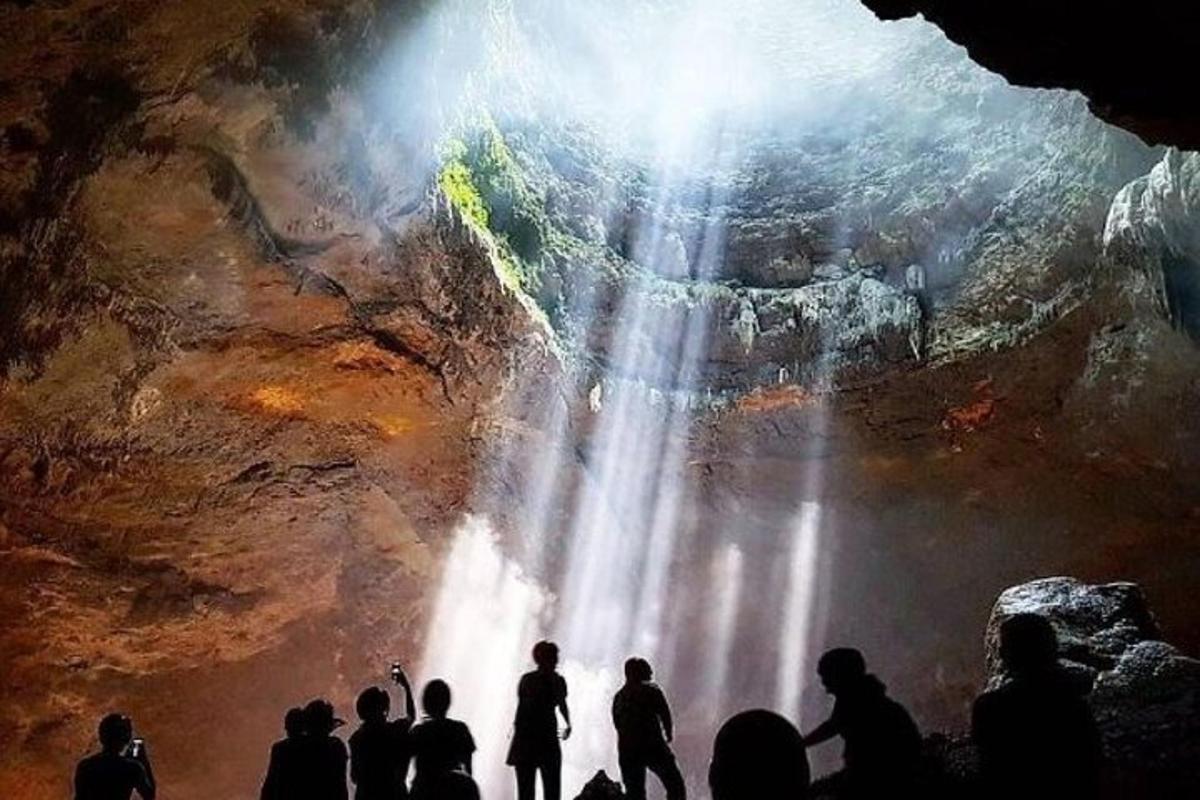sekelompok orang berdiri di depan air terjun