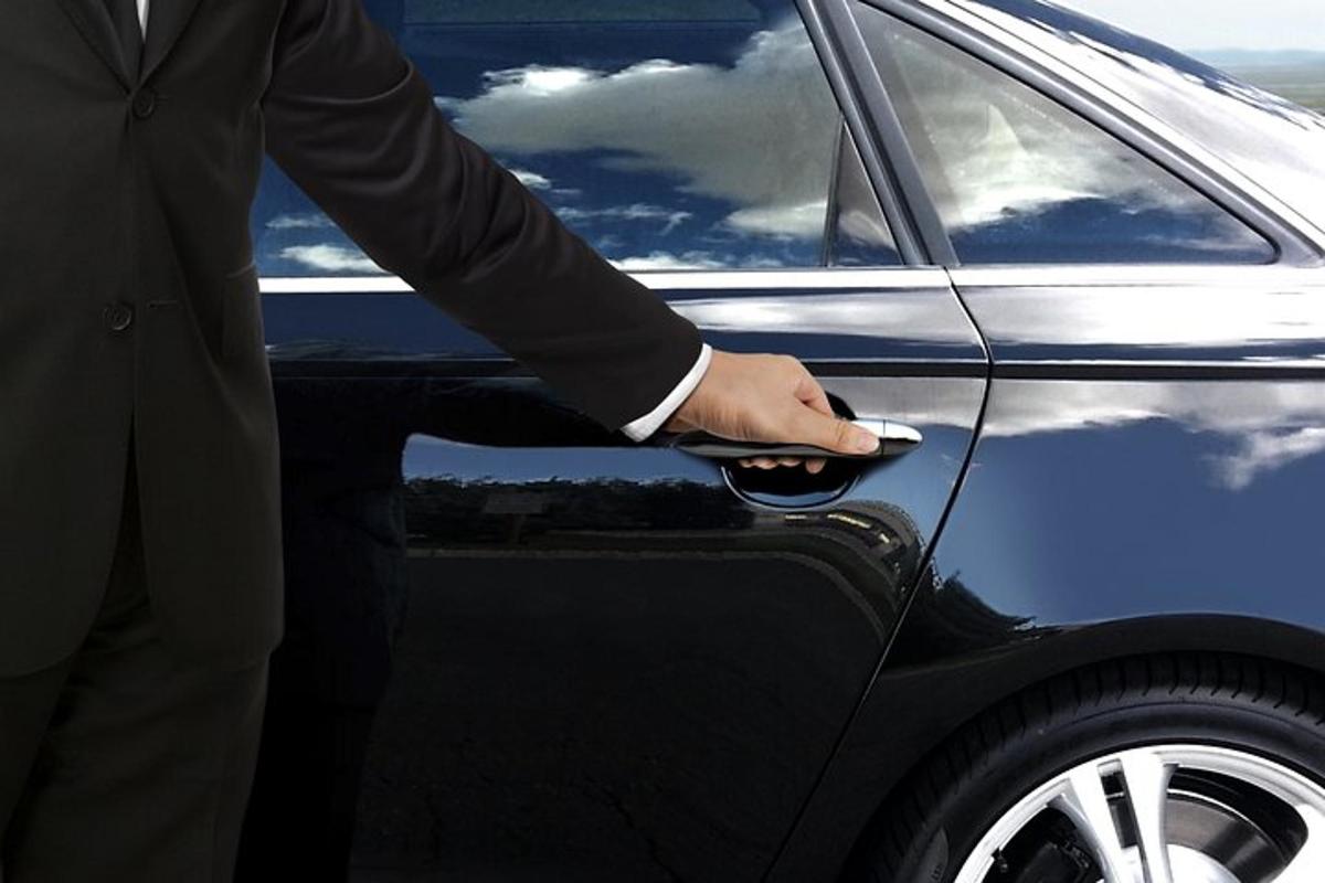 một người đàn ông mặc vest đang mở khóa cửa xe