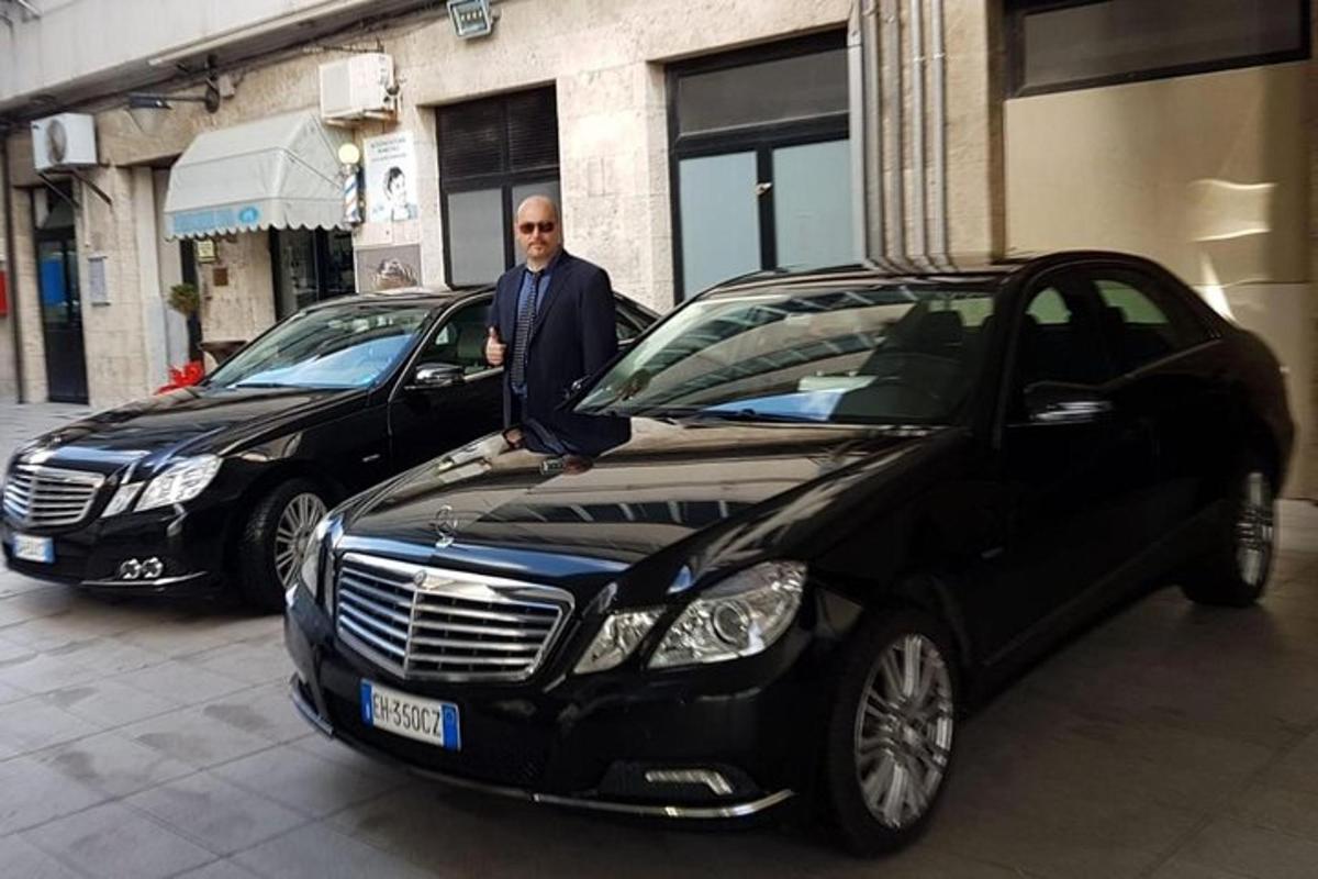 un uomo in piedi accanto a due auto parcheggiate