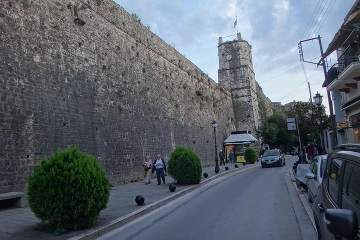 zwei Menschen gehen eine Straße entlang neben einer großen Mauer