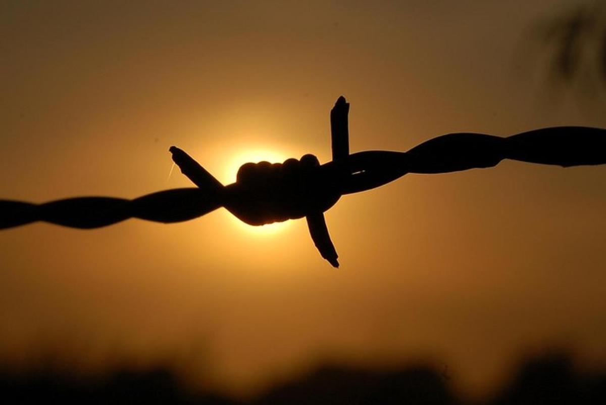 μια σιλουέτα ενός φράχτη με το ηλιοβασίλεμα στο φόντο