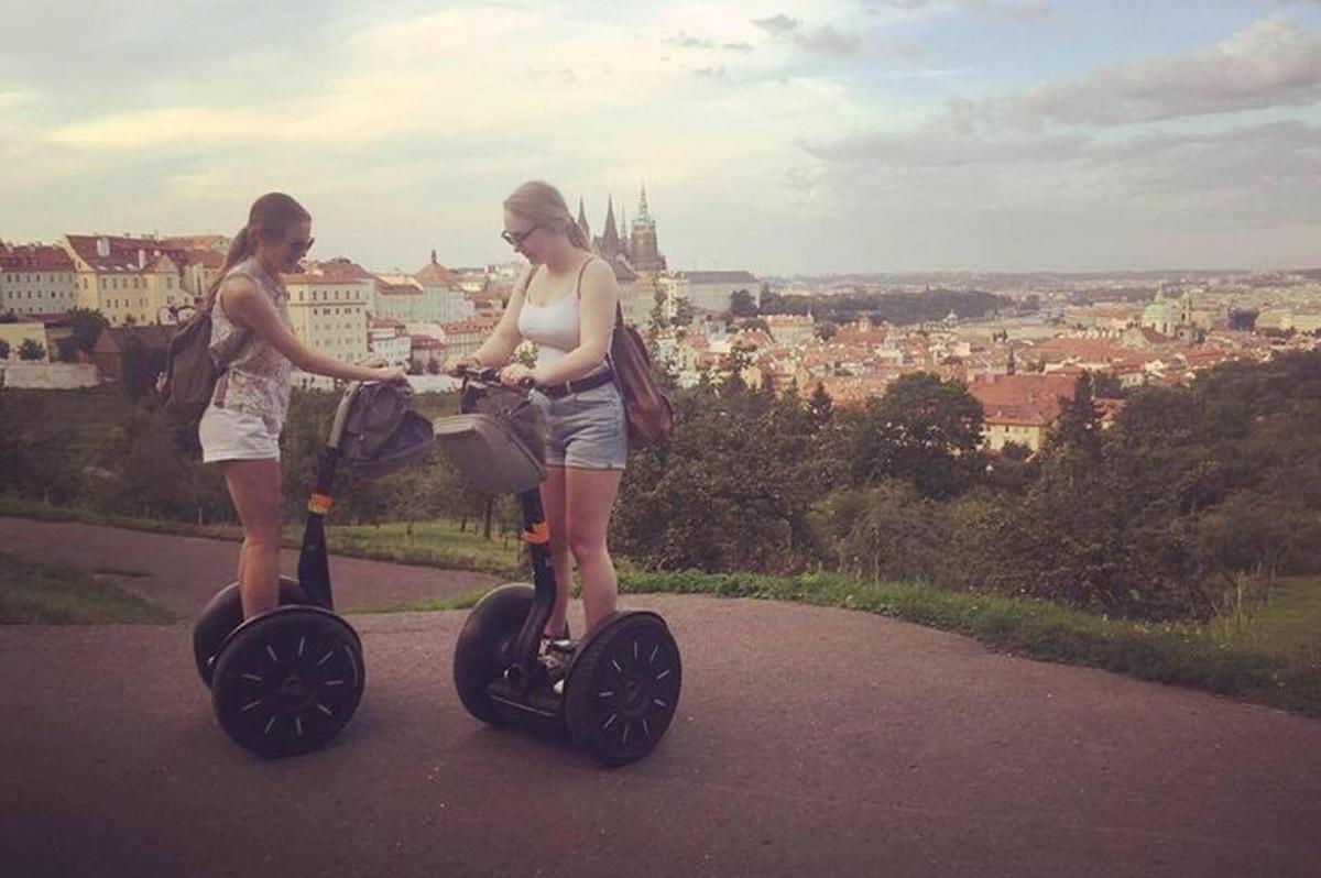 dvě ženy stojící na elektrické koloběžce a dívající se na město