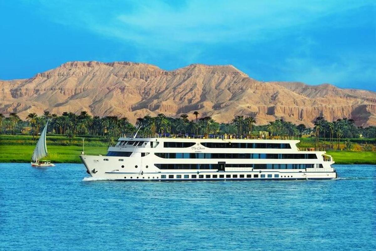 a large cruise ship on the water with a sailboat