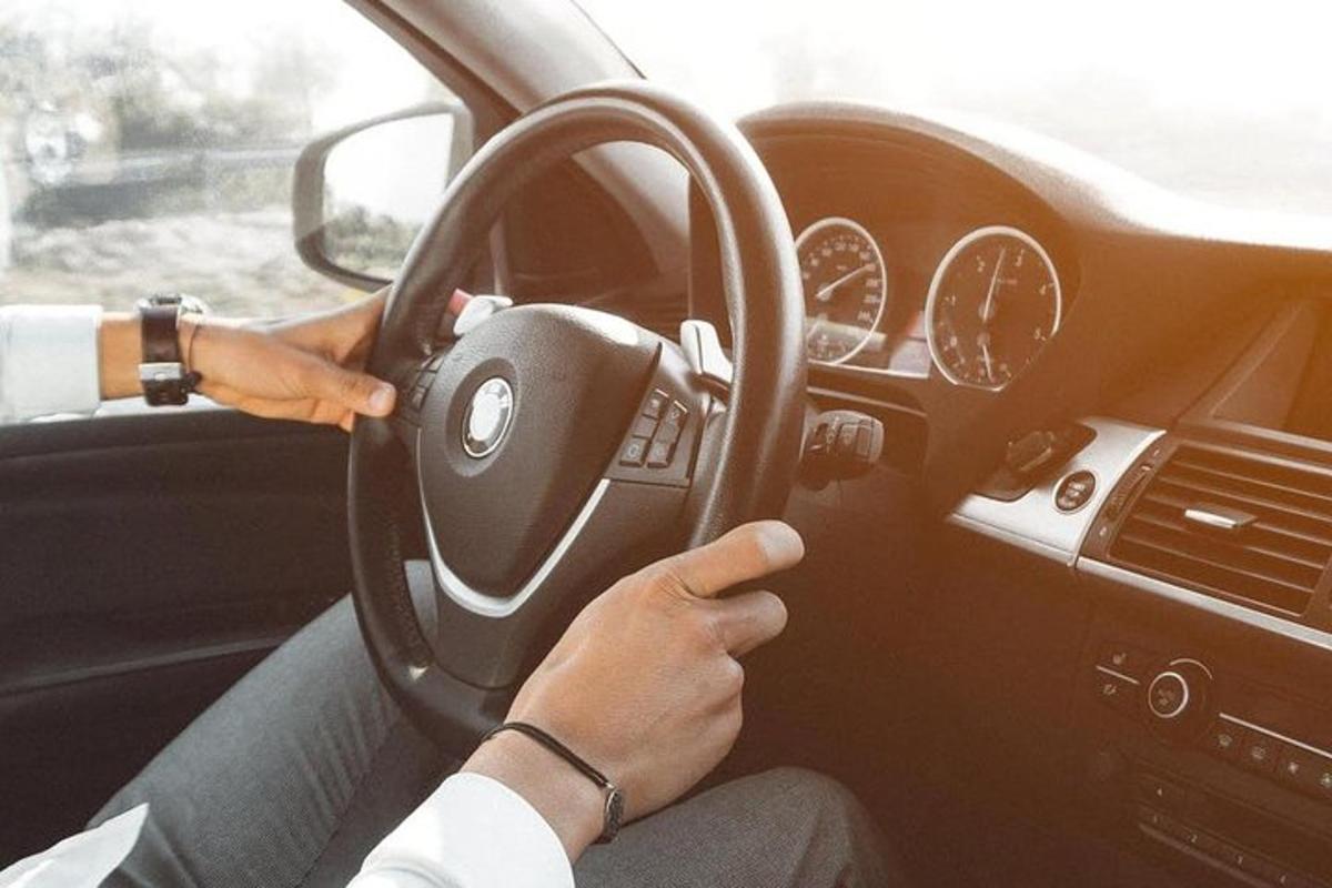 seseorang memandu kereta dengan tangan mereka pada stereng