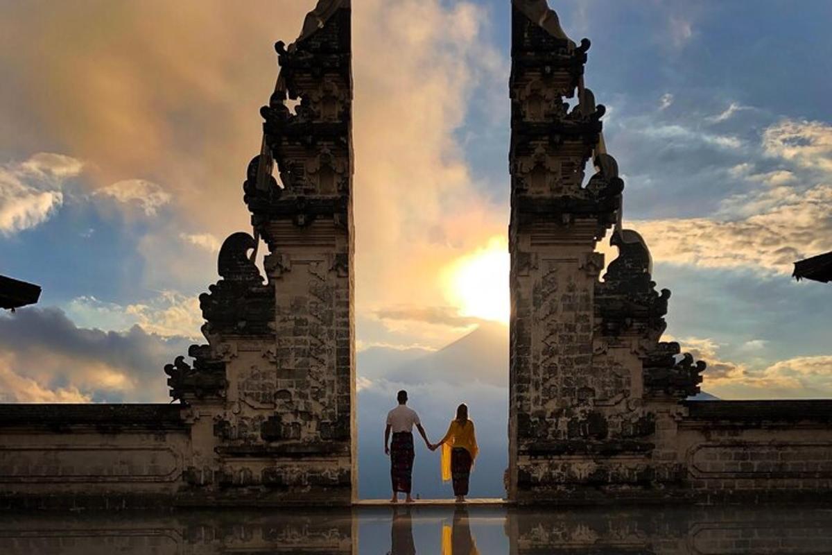 a man and a woman walking through a gate with the sunset