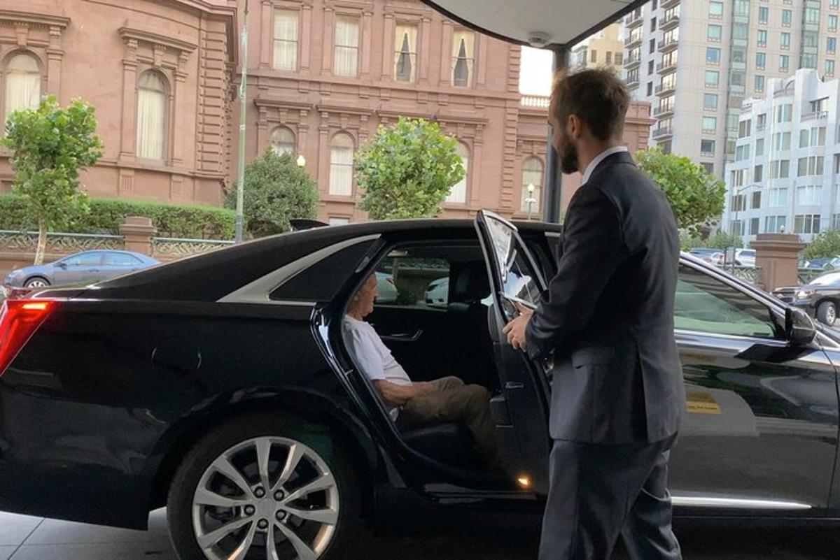 um homem de terno parado ao lado de um carro