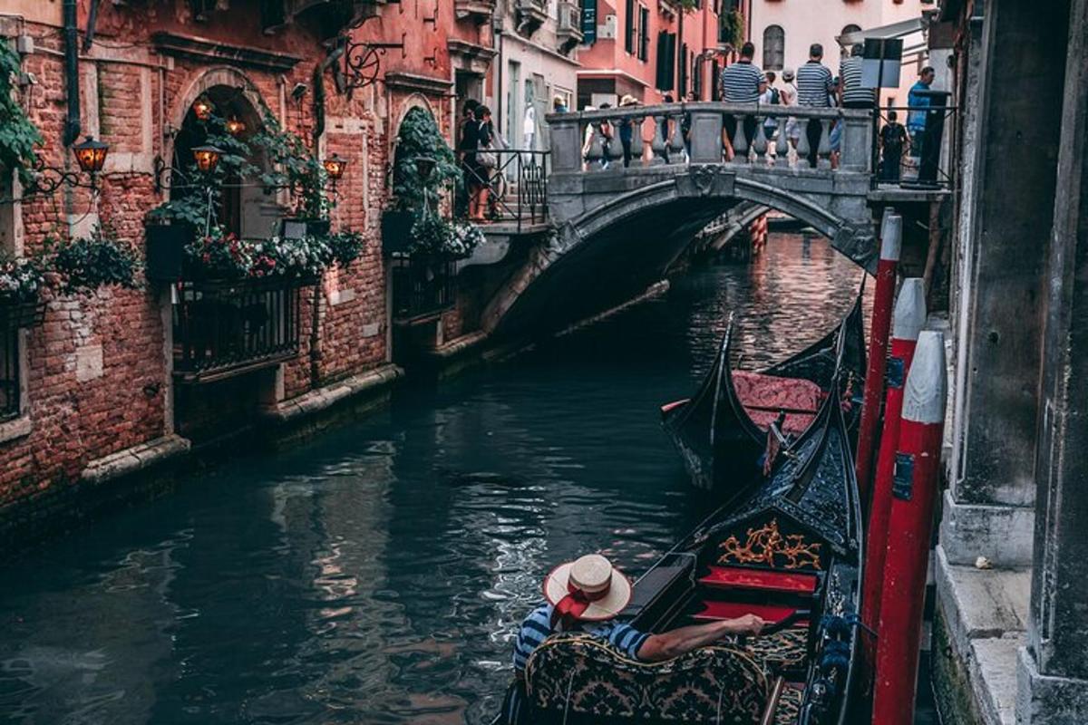 una persona que baixa en góndola per un canal amb un pont