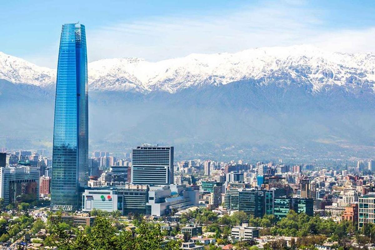 a city with a tall building and snow covered mountains