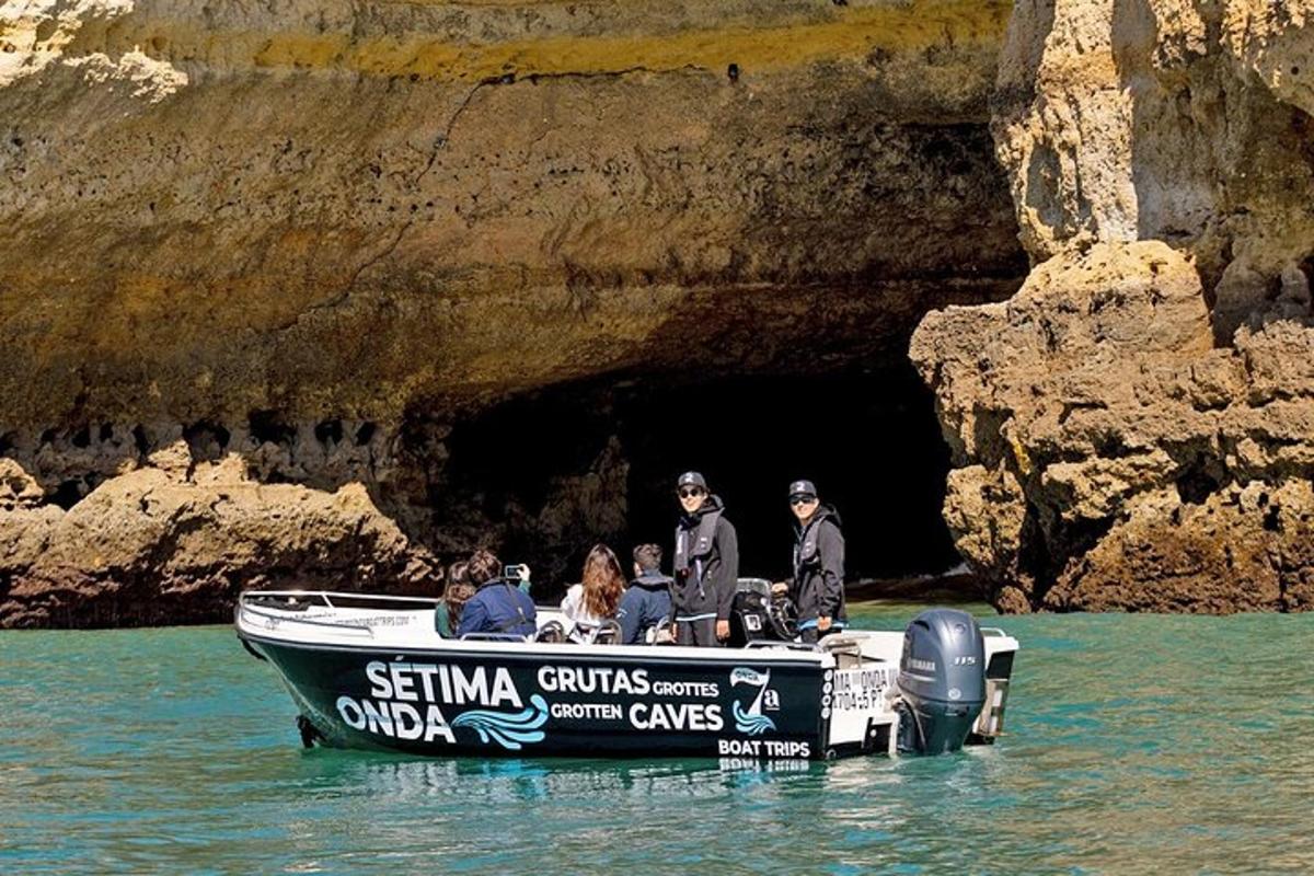 Un grupo de personas en un bote frente a una cueva.