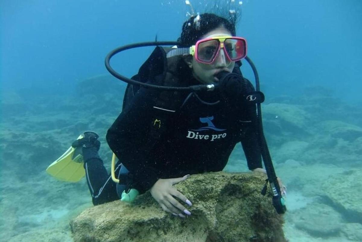 человек в водолазном костюме сидит на камне в воде