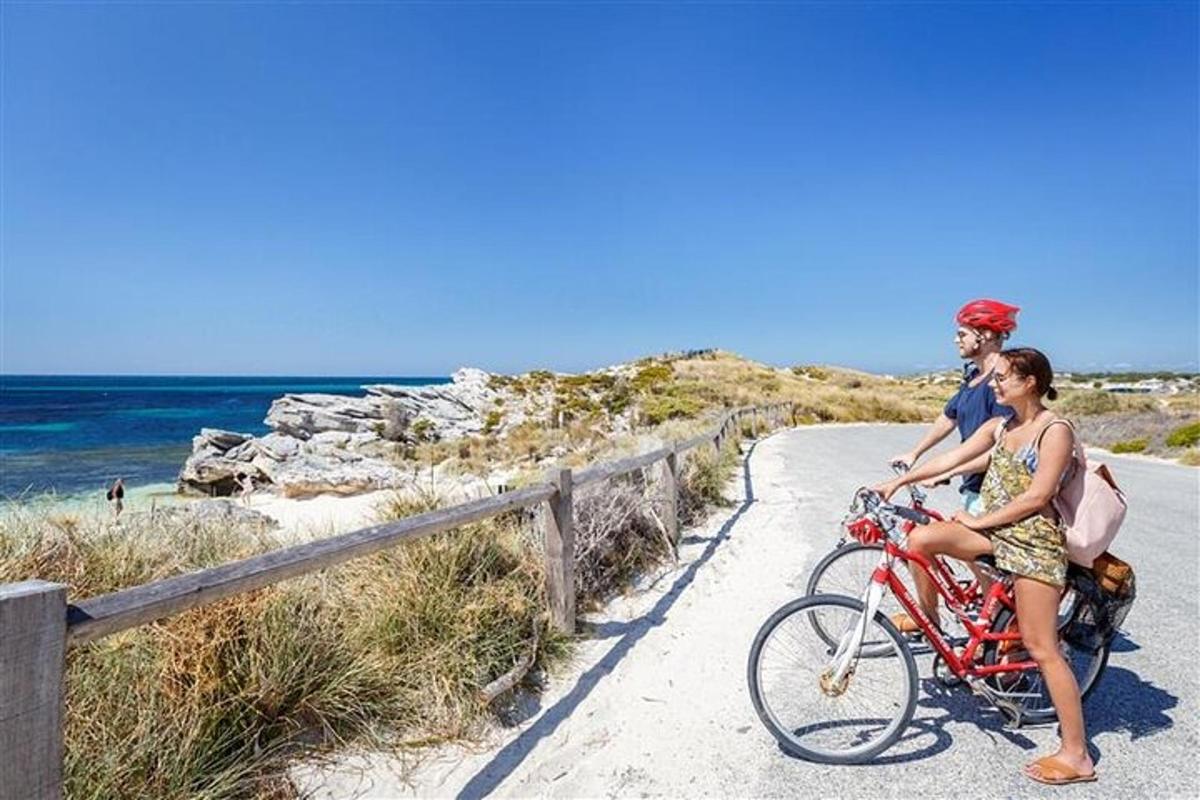 a man and a woman riding a bike on the beach