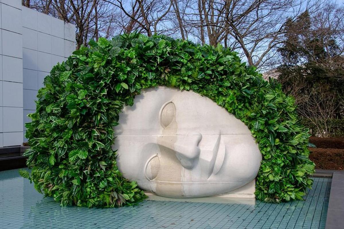 uma estátua com uma cerca verde ao redor