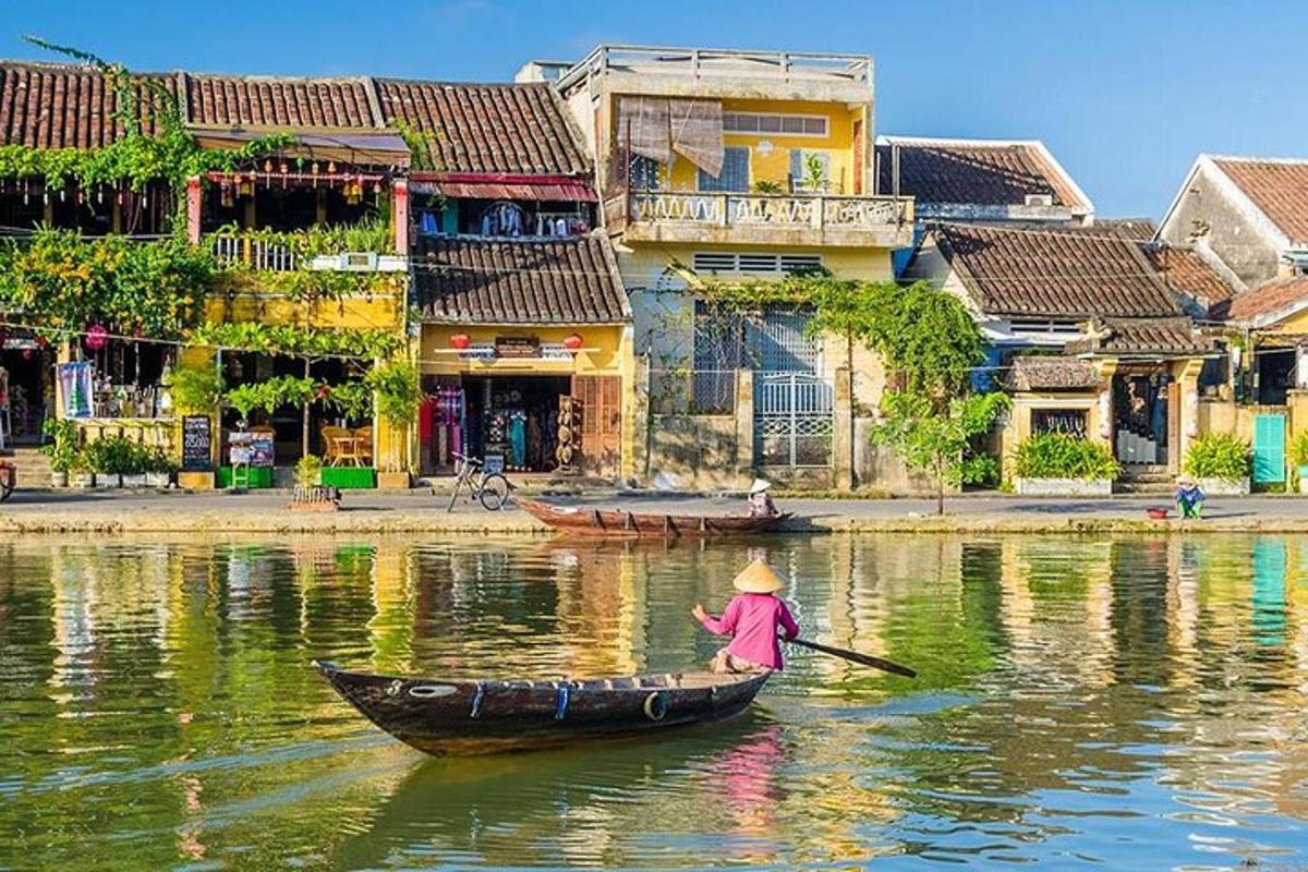 một người trên thuyền trên sông có những tòa nhà