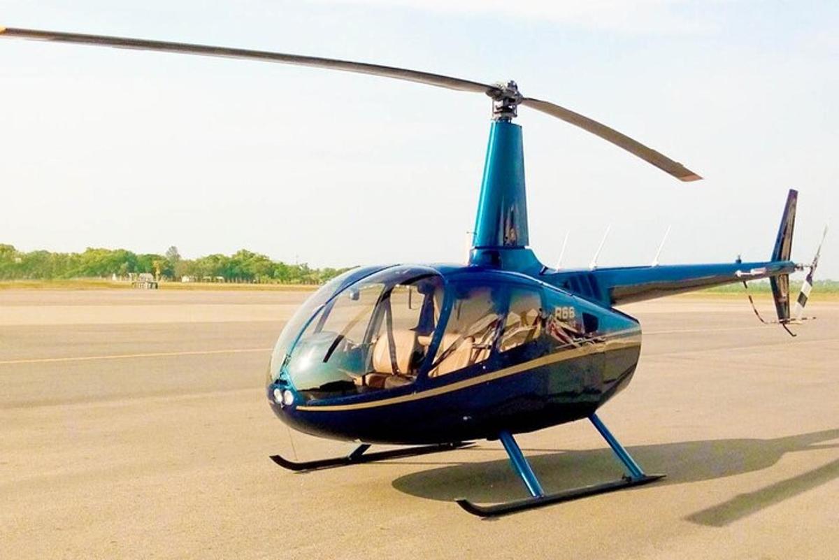 Un pequeño helicóptero azul estacionado en una pista