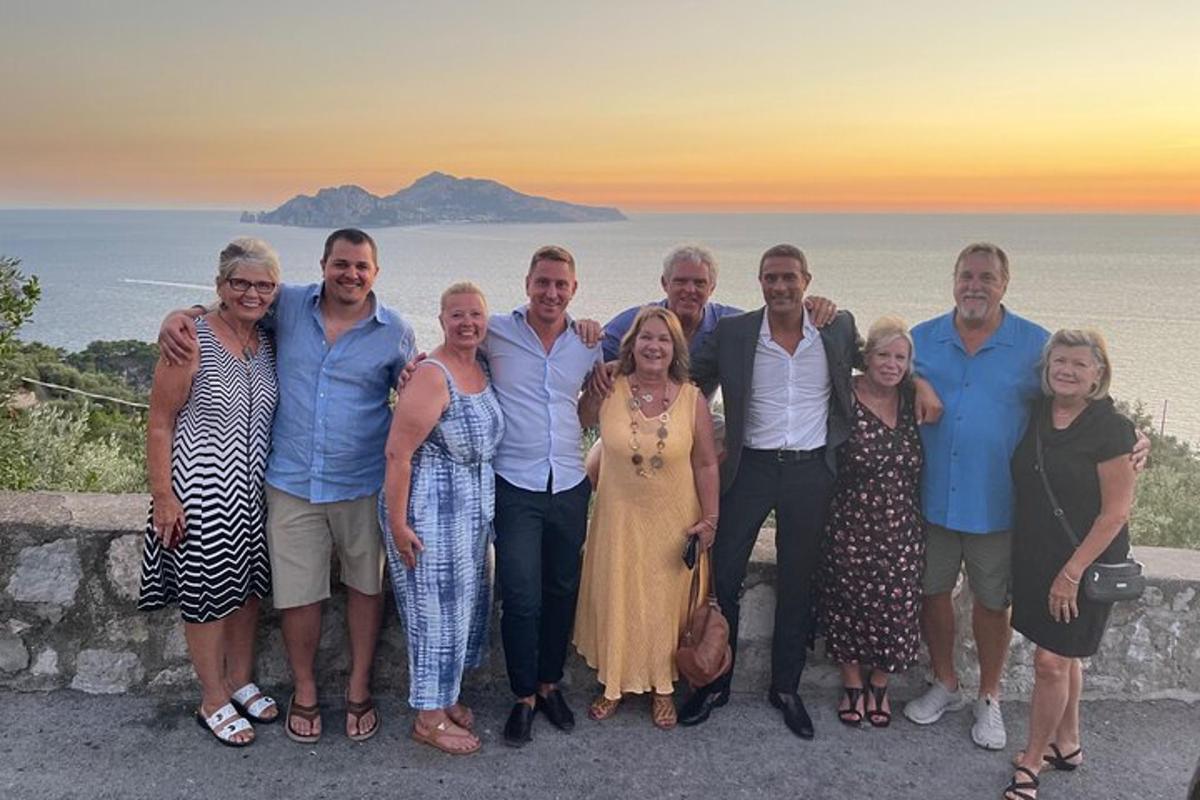 en gruppe mennesker poserer for et bilde foran havet