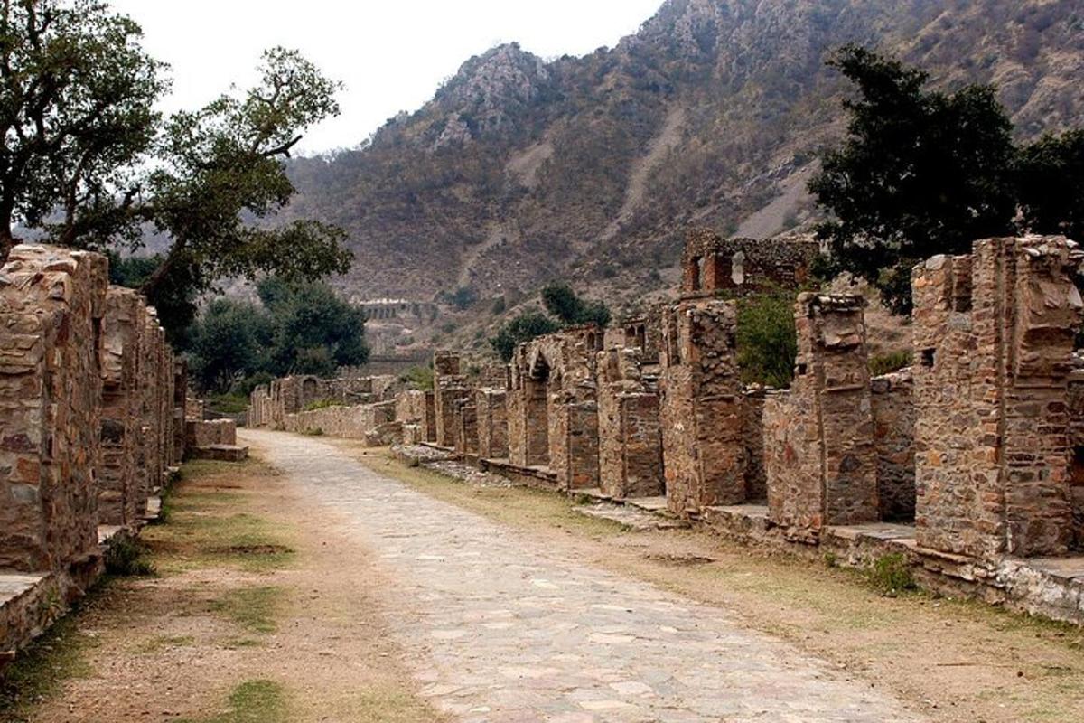 一条土路，两旁都是废墟，背景是群山