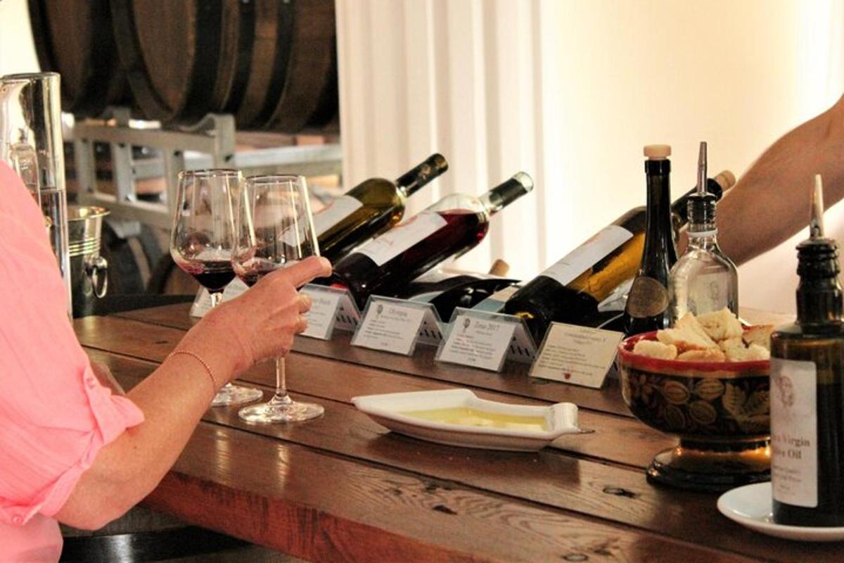 a woman holding a glass of wine on a table with wine bottles