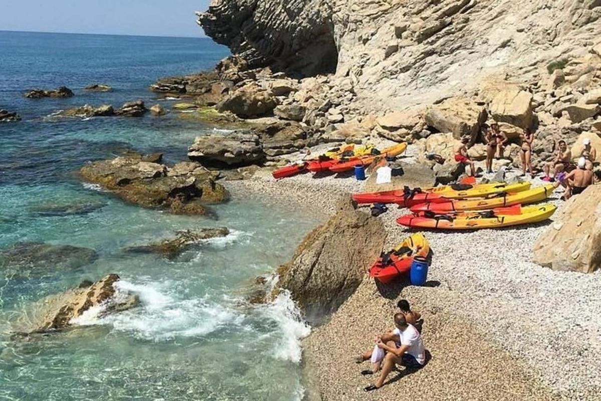 skupina ljudi na skalnati plaži s čolni