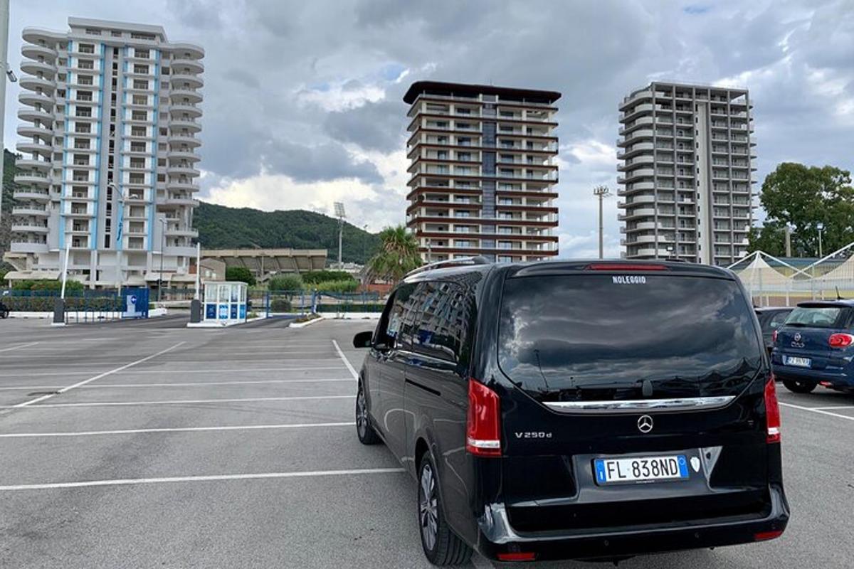 un furgone nero parcheggiato in un parcheggio con edifici alti
