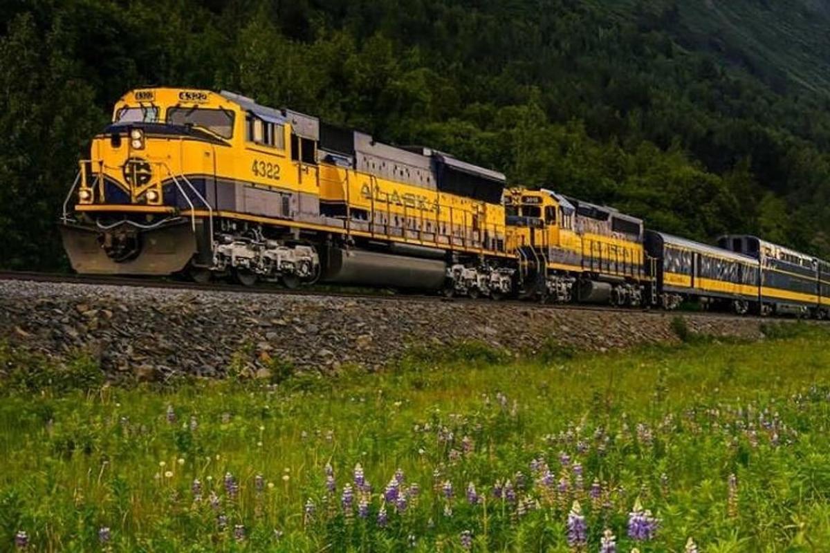 um trem amarelo está viajando pelos trilhos