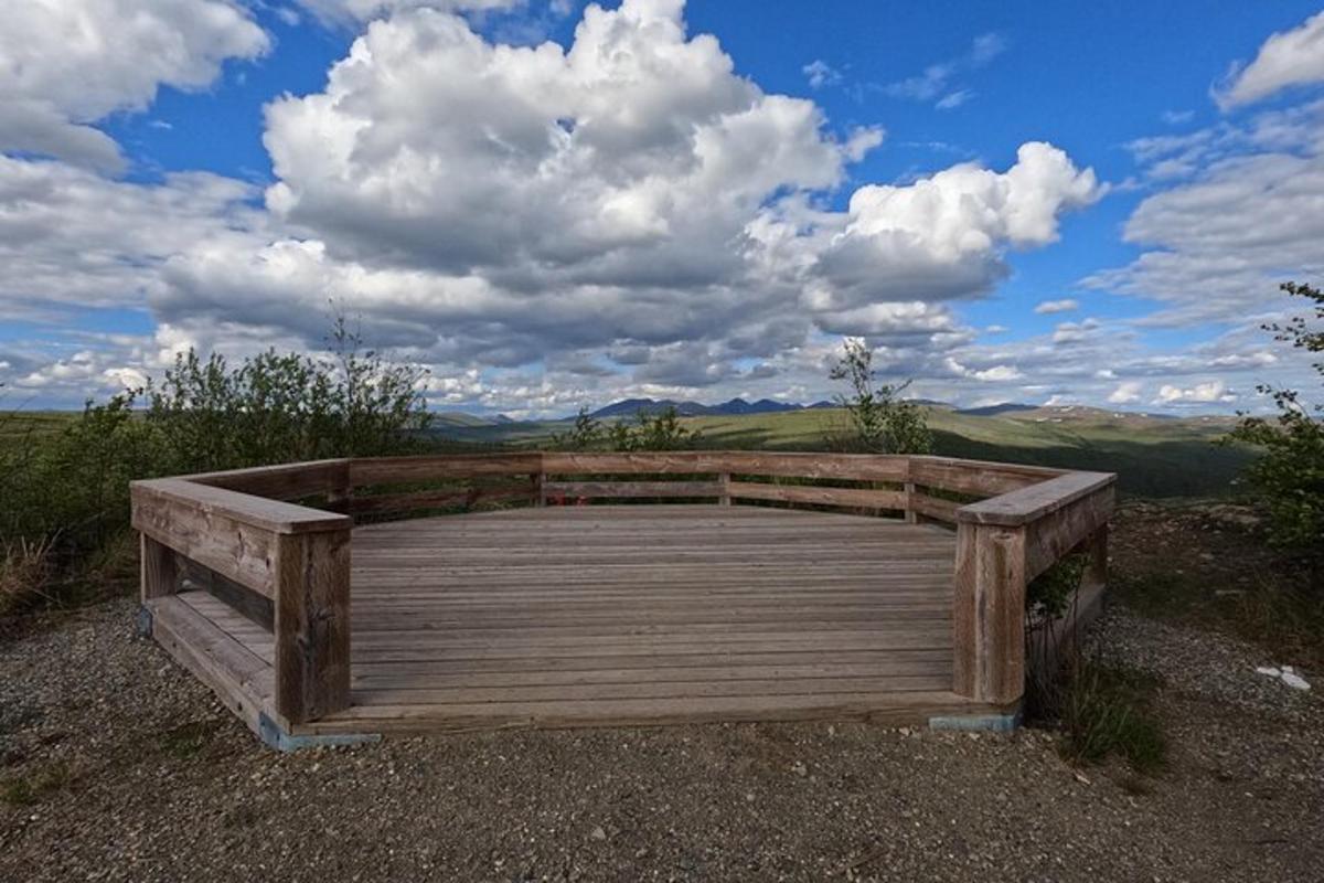 un ponte di legno su una collina con un cielo nuvoloso