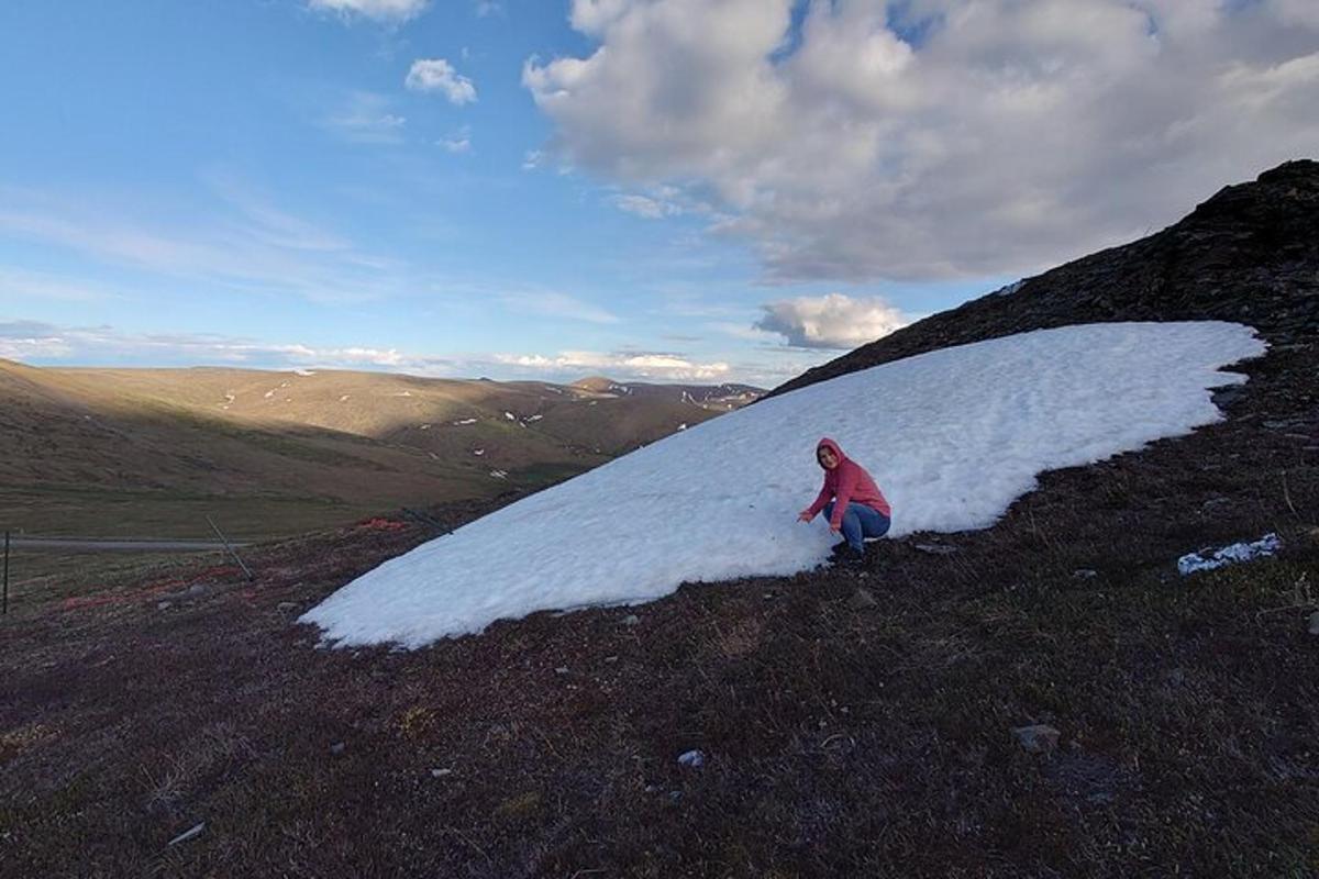 en person som står på toppen av en snødekt ås