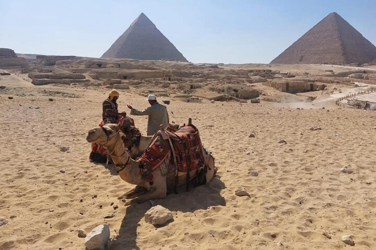 dvaja ľudia jazdiaci na ťave pred pyramídami