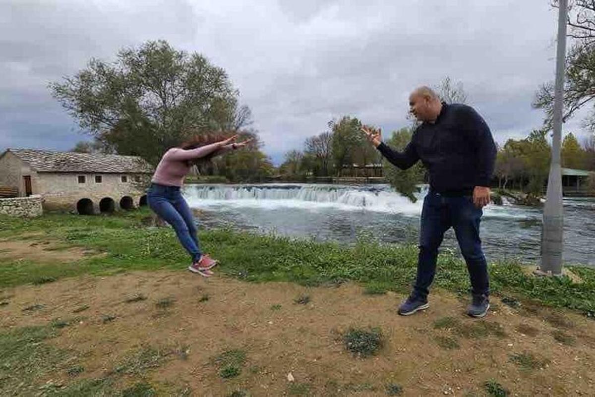 dues persones juguen al frisbee davant d'una cascada