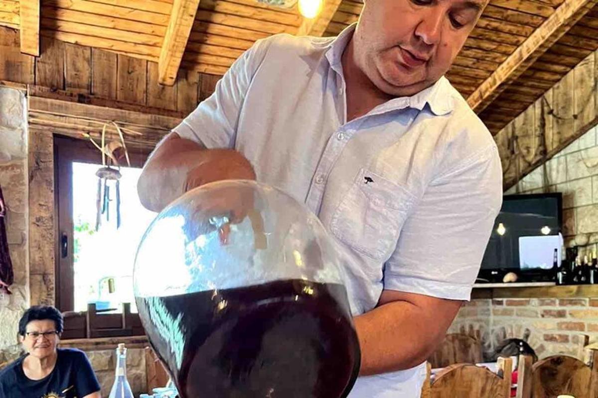 seorang lelaki sedang menuangkan segelas wain