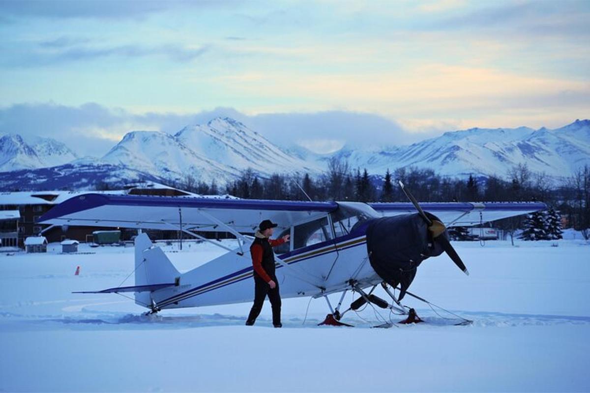 a man standing next to an airplane in the snow
