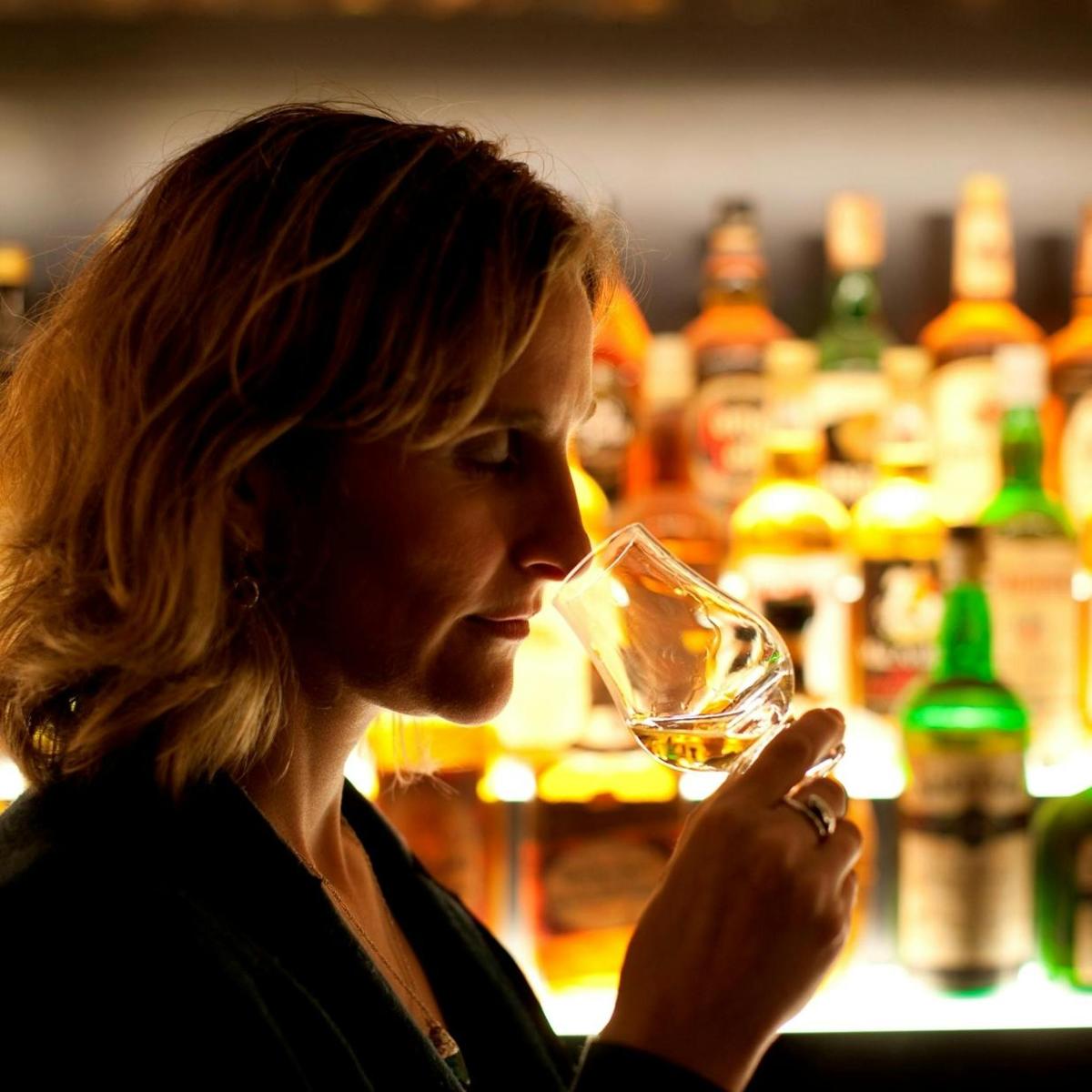 žena drži čašu vina ispred bara