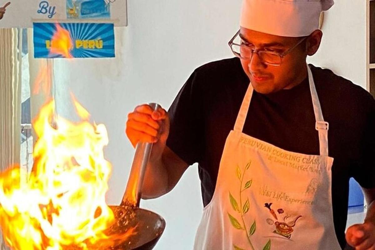 un uomo con un grembiule che cucina cibo in una padella