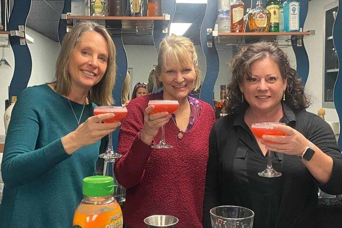 three women holding up wine glasses at a bar