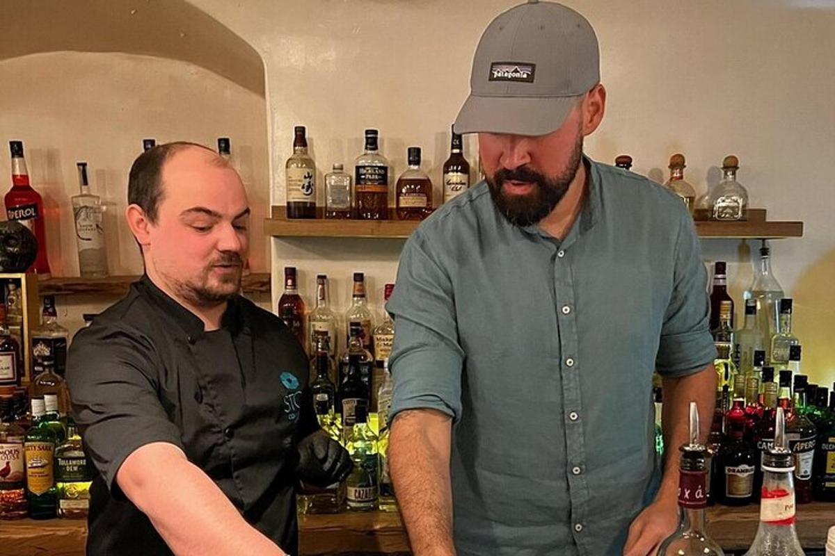 dva moška stojita za šankom s steklenicama vina