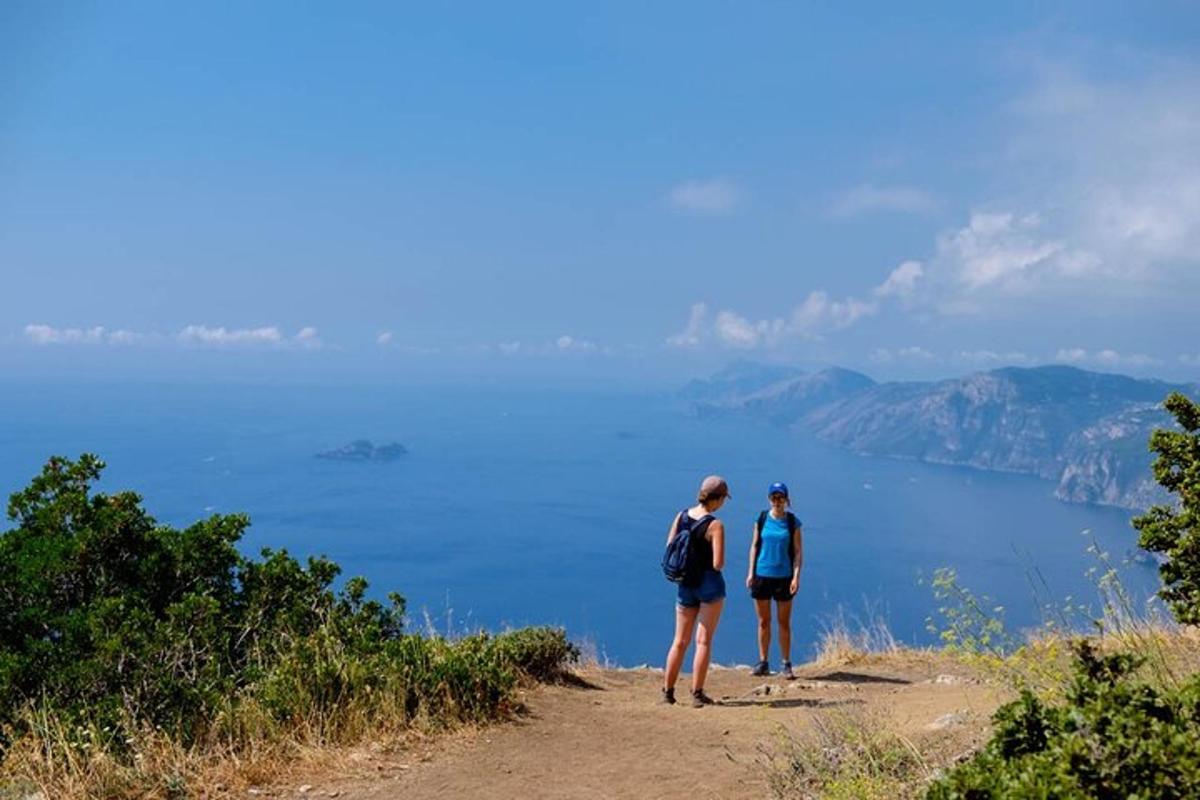 due persone in piedi su una strada sterrata che guardano l'acqua