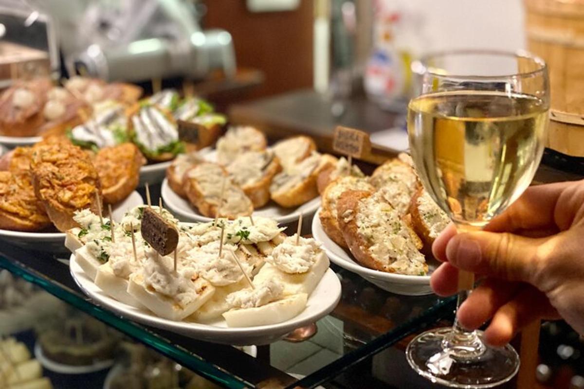 una persona che tiene in mano un bicchiere di vino accanto a piatti di cibo