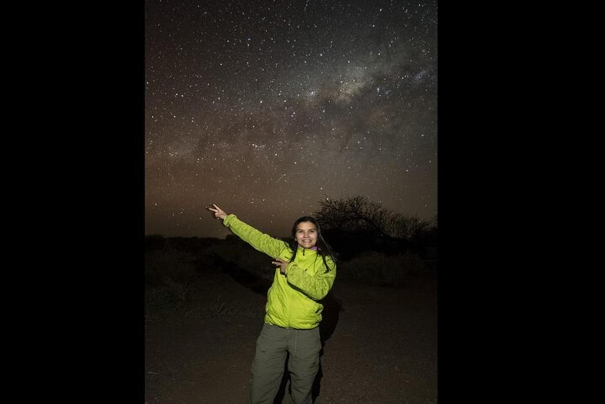 a woman pointing up at the night sky