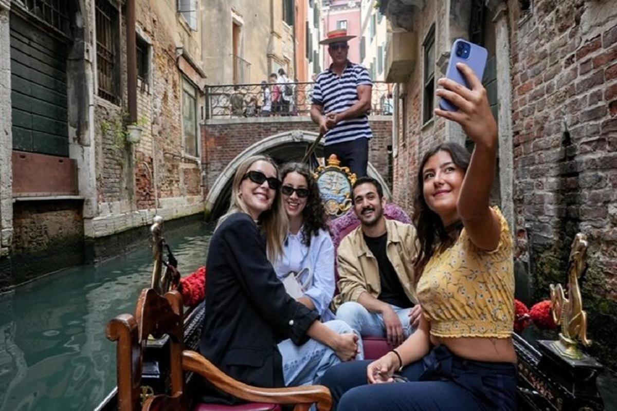 un gruppo di persone che navigano in gondola lungo un canale