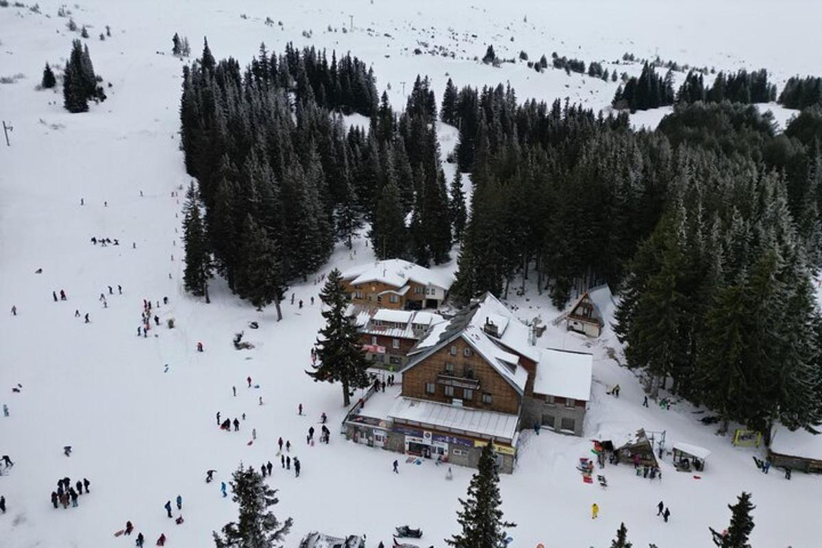 a group of people standing in the snow near a ski lodge