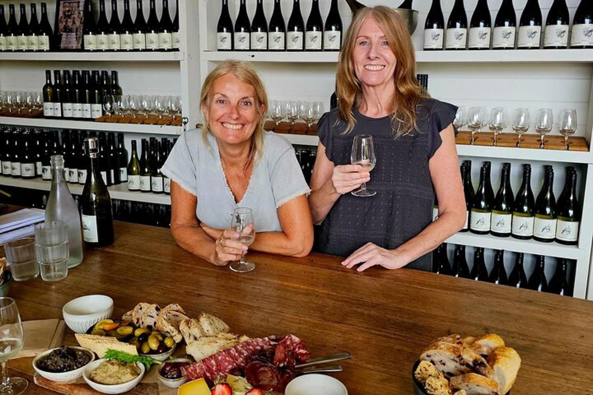 two women standing behind a bar with wine glasses