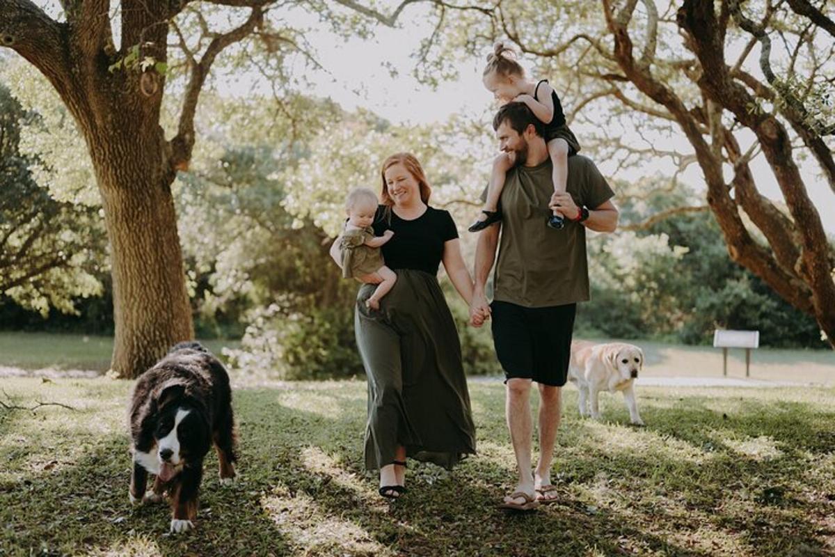 a man and woman walking with a baby and two dogs