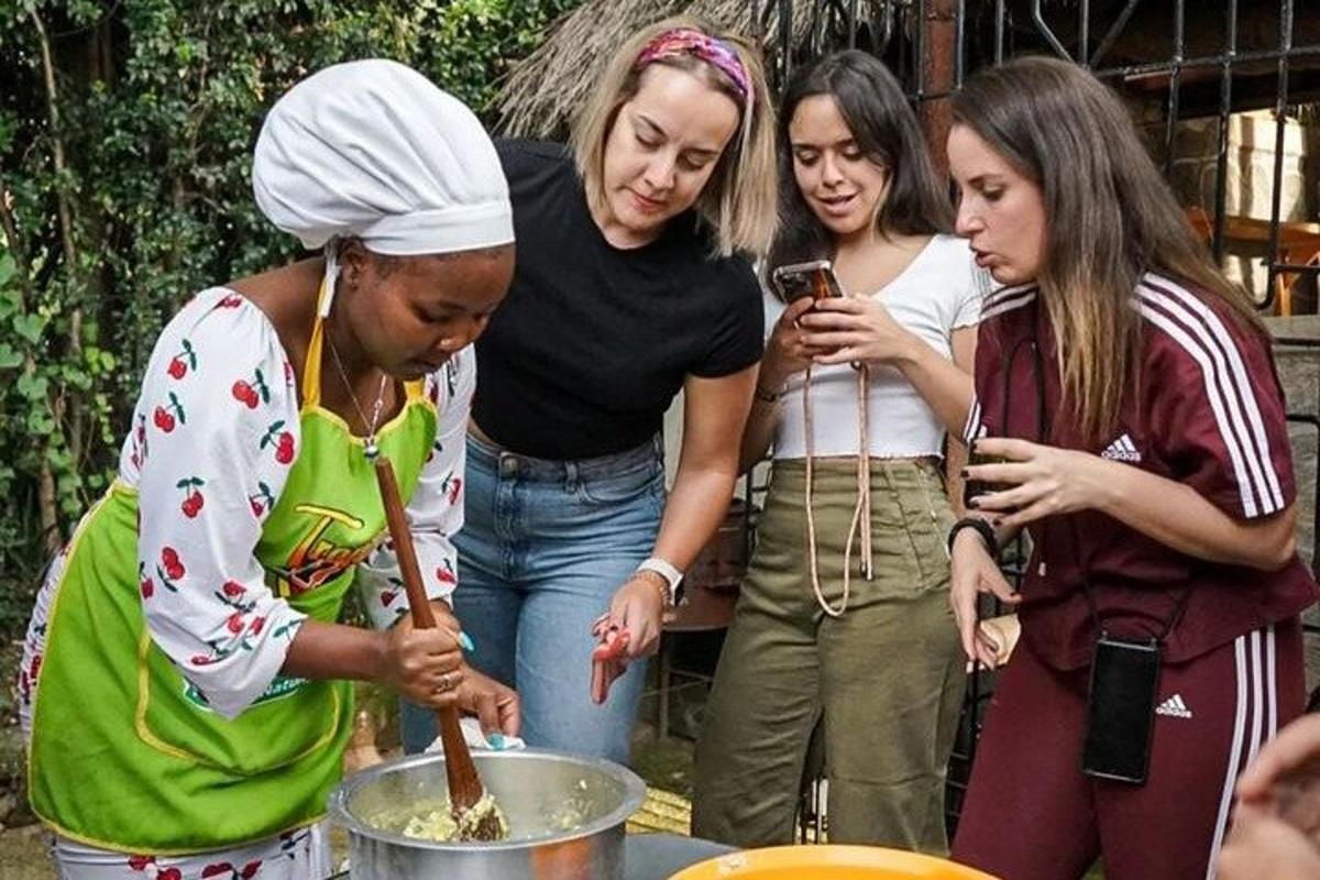 a group of women standing around a pot of food