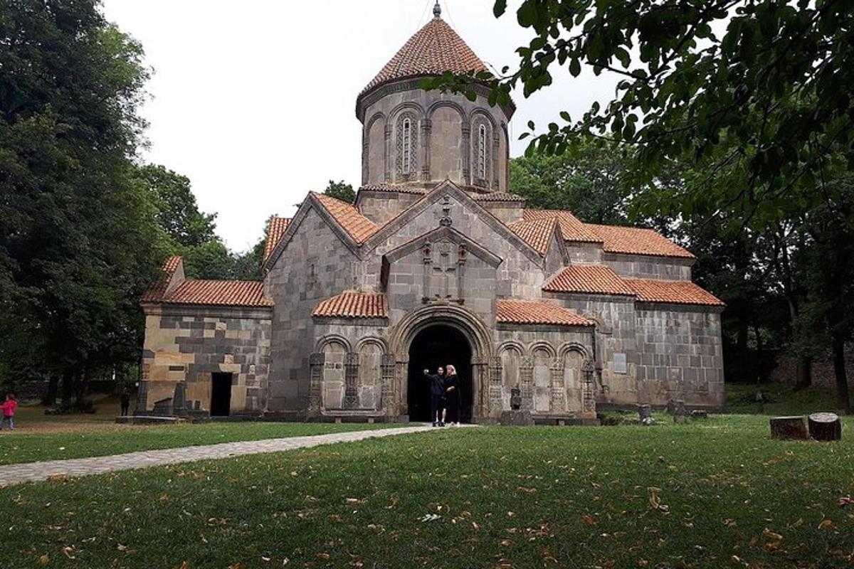 una vecchia chiesa in pietra con una torre dell'orologio in un parco