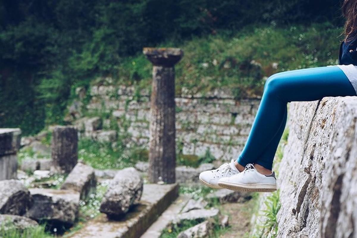 seorang wanita duduk di atas batu memakai legging biru