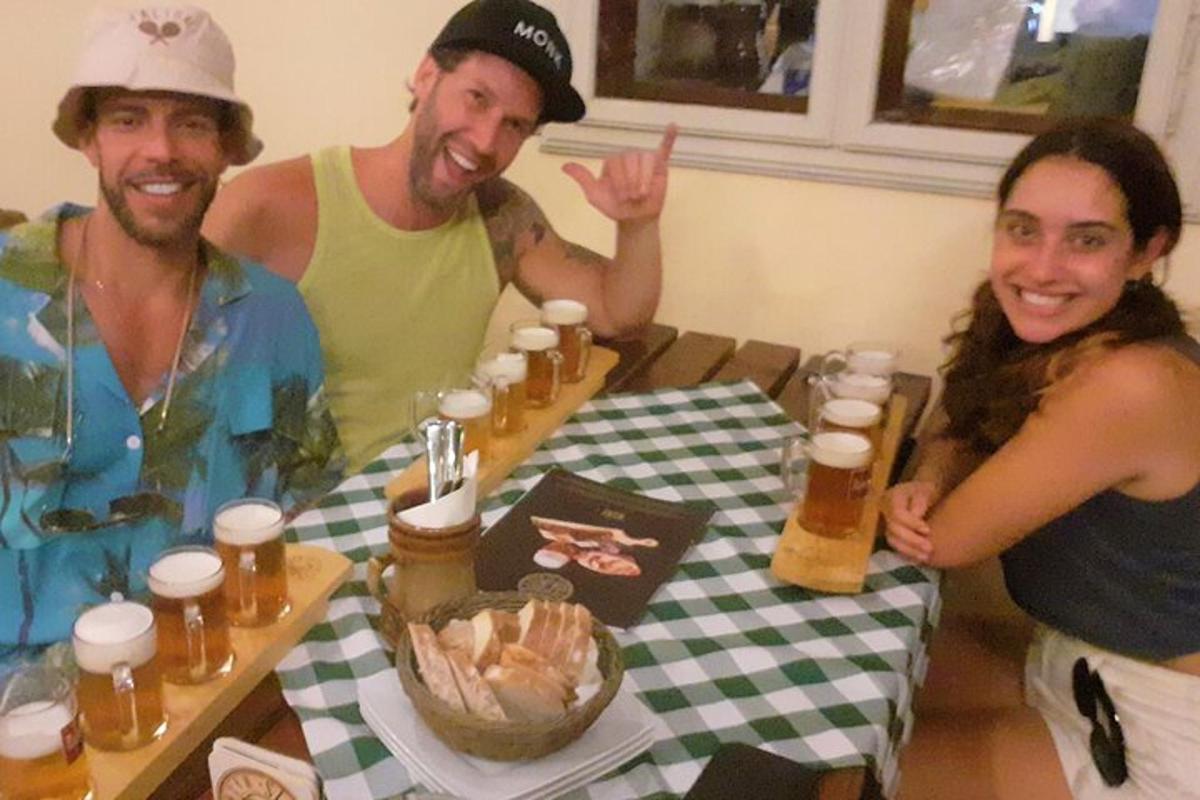 skupina tří lidí sedících u stolu s pivem